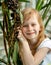 Portrait, little girl seven years, sitting next palm tree