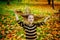 Portrait of a little girl in a striped sweater, tossing her hair in an autumn Park among yellow maple leaves