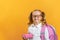 Portrait of a little girl students in glasses with a backpack and lunchbox on a yellow background. Back to school.