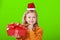 Portrait of a little girl in a sweater and a santa claus hat on a green isolated background.