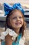 Portrait of a little girl three years with the blue bow on her head, which is smiling