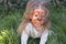 Portrait of a little girl with tiger aqua makeup, smiling and sitting in the green grass.