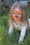 Portrait of a little girl with tiger aqua makeup, smiling and sitting in a park.