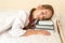 Portrait of little girl using pile of books instead of pillow