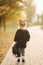 Portrait of little girl walking in the part in autumn. Blond hairl female kid outside. Warm autumn. Back view of kid