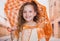 Portrait of little girl wearing a beautiful colonial costume and holding an orange umbrella in a blurred background