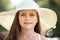 Portrait of a little girl wearing a big hat, beautiful sunny day, bright sun and shadows, face closeup
