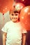 Portrait of a little happy candid smiling caucasian five year old kid boy in white t-shirt with red balloons against the backgroun