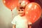 Portrait of a little happy candid smiling caucasian five year old kid boy in white t-shirt with red balloons against the backgroun