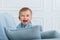 Portrait of a little laugh boy child playing on the sofa in living room