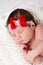 Portrait of little newborn baby girl with a red bow on her head. Sleeping kid.