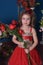 Portrait of a little princess girl in a red dress with flowers i