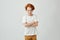Portrait of little red haired boy with cute freckles in white tshirt looking in camera with offended expression when his