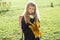 Portrait of little schoolgirl with yellow maple leaves school bag, on sunny autumn day