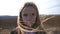 Portrait of little serious girl looks into camera against the background of plowed field at organic farm. Small female