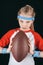 Portrait of little sportive girl with rugby ball isolated on black