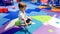 Portrait of little toddler boy crawling and playing on the colorful children palyground covered with soft mats in