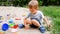 Portrait of little toddler boy playing with toys and digging sand in sandbox at park