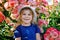 Portrait of little toddler girl in blossoming rose garden. Cute beautiful lovely child having fun with roses and flowers