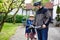 Portrait of little toddler girl with security helmet on the head sitting in bike seat and her father with bicycle. Safe