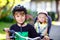Portrait of little toddler girl with security helmet sitting in bike seat of brother. Kid boy on bicycle with lovely