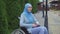 Portrait lonely sad young muslim woman disabled in a traditional scarf sitting in a wheelchair in the park