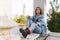 Portrait of a longing pensive teenage girl dressed in denim and boots, sitting, looking at camera. Horizontal view.