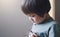 Portrait of lonly kid boy with sad face playing alone, Bored Child looking at tank toy with thinking face