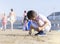 Portrait of lonly little boy playing alone on beach, Kid using shell writing  on the sand. Child playing on the beach during