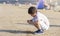 Portrait of lonly little boy playing alone on beach, Kid using shell writing  on the sand. Child playing on the beach during