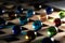 A portrait of a lot of different marbles in different colors, lying on a wooden roster casting a colorful shadow onto the wooden