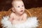 Portrait of lovely baby in woven basket on pile of straw background