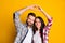 Portrait of lovely cheery couple showing up heart symbol shape idyllic isolated over bright yellow color background