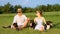 PORTRAIT: Lovely couple sits in grassy field with their three obedient puppies.