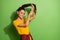 Portrait of lovely funky cheerful girl wearing modern hairdo cutting curls  over bright green color background