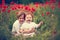 Portrait of lovely kids, brothers sitting in poppy flower field at summer day