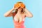 Portrait of lovely woman in swimsuit covering eyes with fresh cut orange and sending air kiss with pout lips