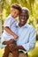 Portrait Of Loving Grandfather Holding Grandson In Arms In Garden At Home