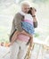 Portrait of loving grandmother carrying granddaughter at home