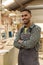 Portrait Of Male Apprentice Working As Carpenter In Furniture Workshop 