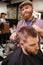 Portrait Of Male Barber Giving Client Haircut In Shop