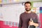 Portrait Of Male Elementary School Teacher Standing In Classroom