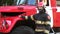 Portrait of male firefighter in helmet and uniform standing near a big red car. Young confident fireman in full