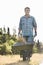 Portrait of male gardener pushing wheelbarrow at garden