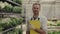 Portrait of the male gardener standing near the cart full of flowers looking at the camera and smiling. People and