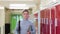 Portrait Of Male High School Student Walking Down Corridor And Smiling At Camera