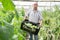 Portrait of male horticulturist standing with crate of cucumbers