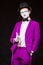 Portrait of male mime artist, isolated on black background. Man in purple suit points and smiles. Symbol of self