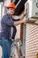 Portrait of male repairman standing on stepladder and repairing air conditioner