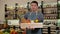 Portrait of a male salesman in an apron with a box of fresh fruit in his hands.